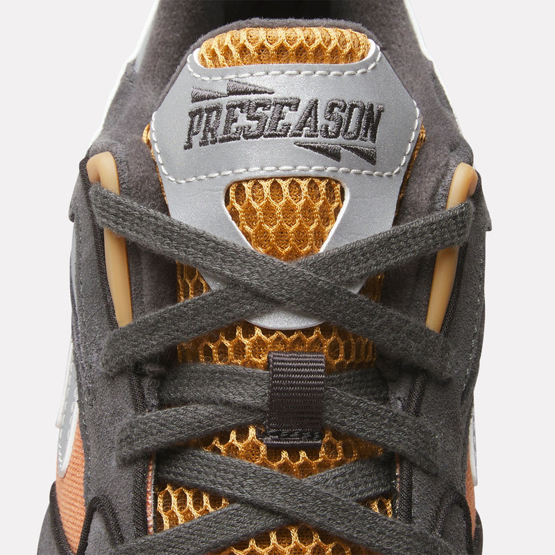 Close-up of a Reebok x Market Preseason 94 Low Shoes tongue featuring gold mesh detailing, dark grey laces, and a grey patch with PRESEASON embroidered in black, framed by decorative stitching—showcasing the signature style of this collaborative training shoe from Reebok.
