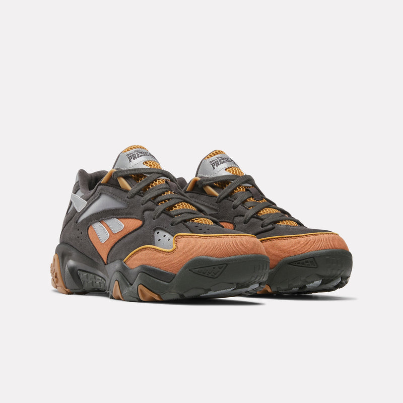 A pair of Reebok x Market Preseason 94 Low Shoes featuring black, grey, and orange suede and mesh panels, chunky soles, and branded tongues, photographed on a white background.