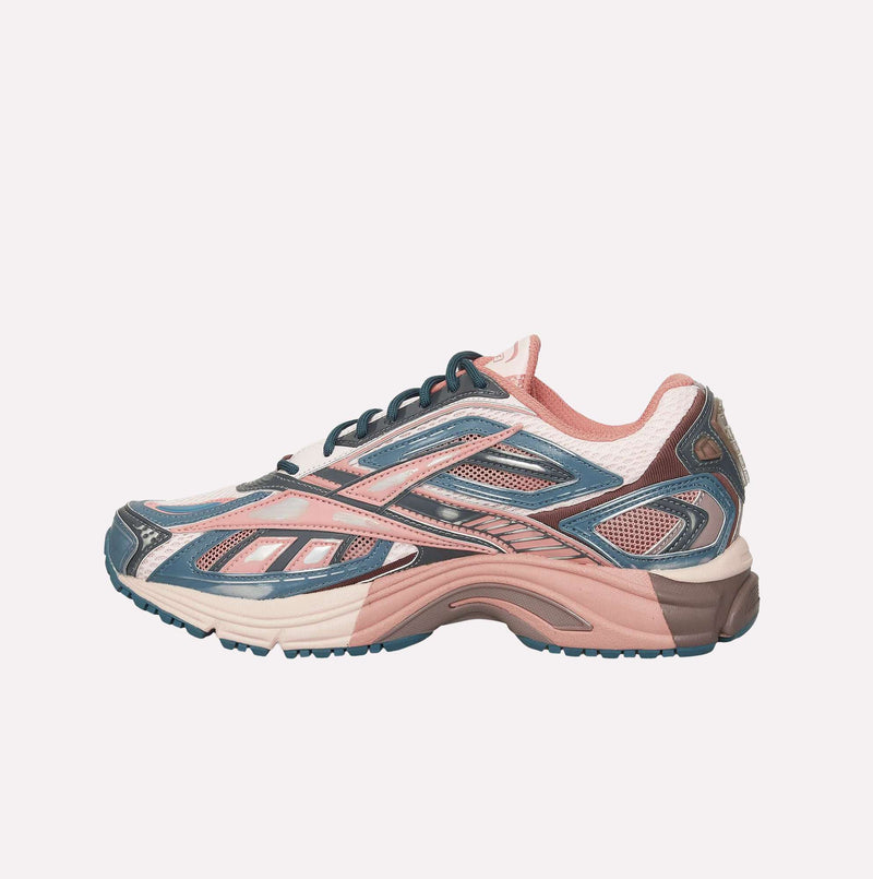 The Reebok Premier Road Ultra LTD Shoes showcase a stylish archival running silhouette with a mix of pink, navy blue, and white mesh and synthetic materials. Highlighted by a chunky dual-density midsole and intricate panel detailing, this sneaker is set against a plain white background.