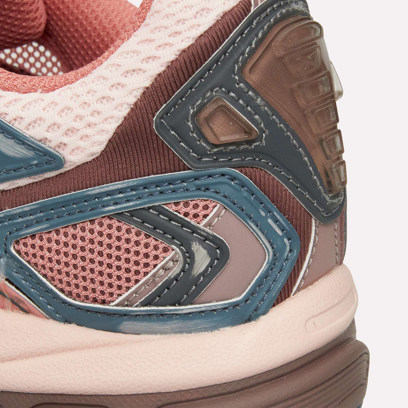Close-up of the heel and side of the Reebok Premier Road Ultra LTD Shoes, showcasing pink mesh with blue and brown overlays and textured materials. The image highlights intricate stitching, a layered design, mixed fabric details, and the dual-density midsole that enhances comfort in this archival running sneaker.
