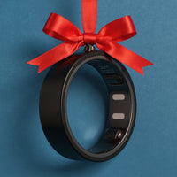 A black circular fitness tracker with a red satin ribbon bow hanging from the top, set against a solid blue background.