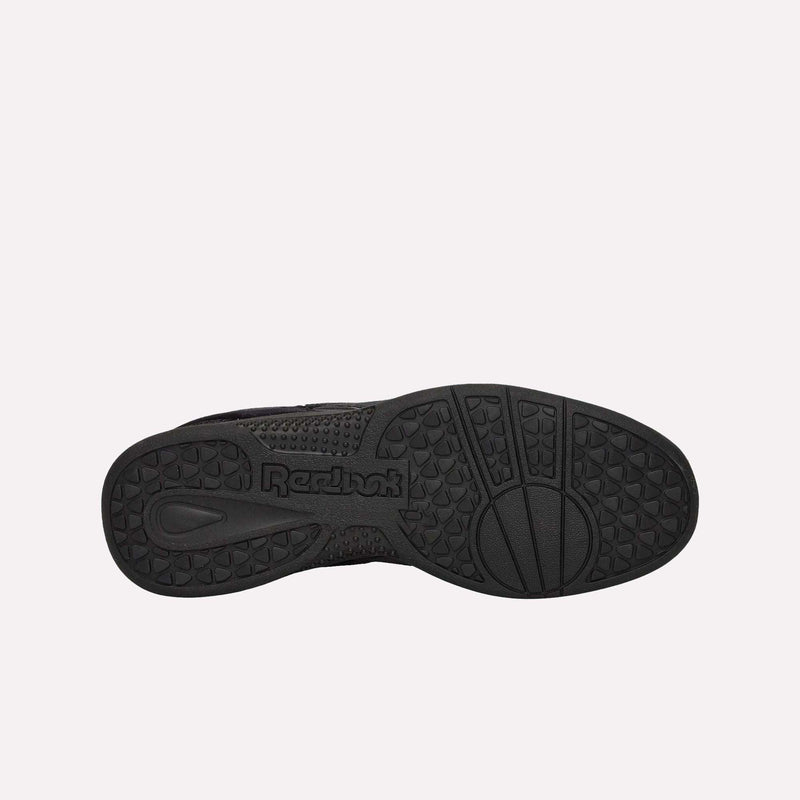 The black rubber sole of the Reebok Pleasures Hammer Street Shoes features textured grip patterns and a centrally stamped Reebok logo, shown from directly beneath against a plain white background. This exclusive release showcases collaboration design details from PLEASURES and pairs seamlessly with its distinctive velvet upper.
