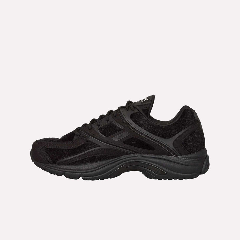The Reebok Pleasures Premier Trinity KFS Shoes are black athletic sneakers with a textured sole and mesh panels, featuring a distinctive pony hair upper, shown in profile against a plain white background.