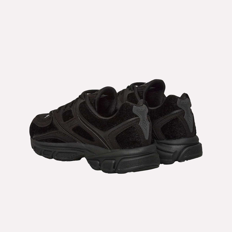 A pair of Reebok Pleasures Premier Trinity KFS Shoes in black, featuring textured pony hair uppers and chunky soles, shown from the back and side on a plain, light background—part of an exclusive collaboration with Pleasures.