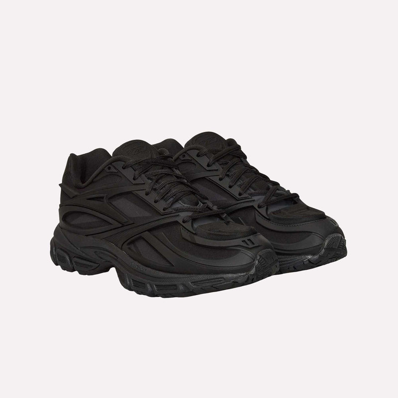 A pair of Reebok Premier Road Modern LTD Shoes in black, featuring textured soles and layered detailing, are displayed side by side on a plain white background; this futuristic sneaker takes inspiration from classic archival running shoe designs.