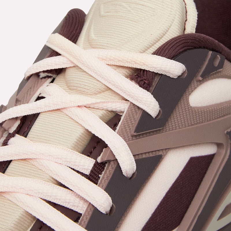 Close-up of the Reebok Premier Road Modern LTD Shoes, featuring cream-colored laces, maroon and cream textile uppers, and plastic overlays in brown and mauve—offering a contemporary reinterpretation of the classic archival running shoe.