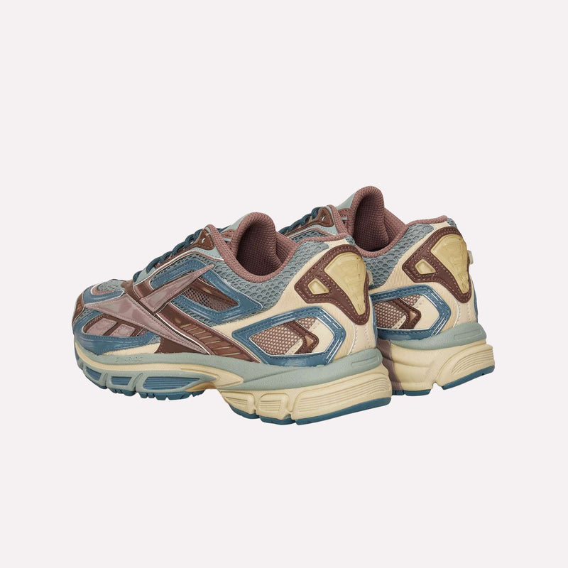 The Reebok Premier Road Ultra LTD Shoes, shown from a rear angle on a plain white background, are a pair of running sneakers in beige with blue and brown accents, featuring a dual-density midsole for enhanced comfort.