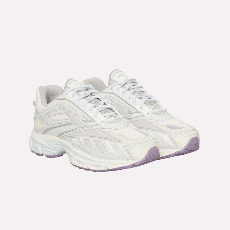 A pair of Reebok Premier Road Ultra LTD Shoes in white with light gray and lavender accents, featuring a chunky sole and mesh panels inspired by archival running designs, are displayed on a light background. These sneakers also offer a dual-density midsole for enhanced comfort and support.
