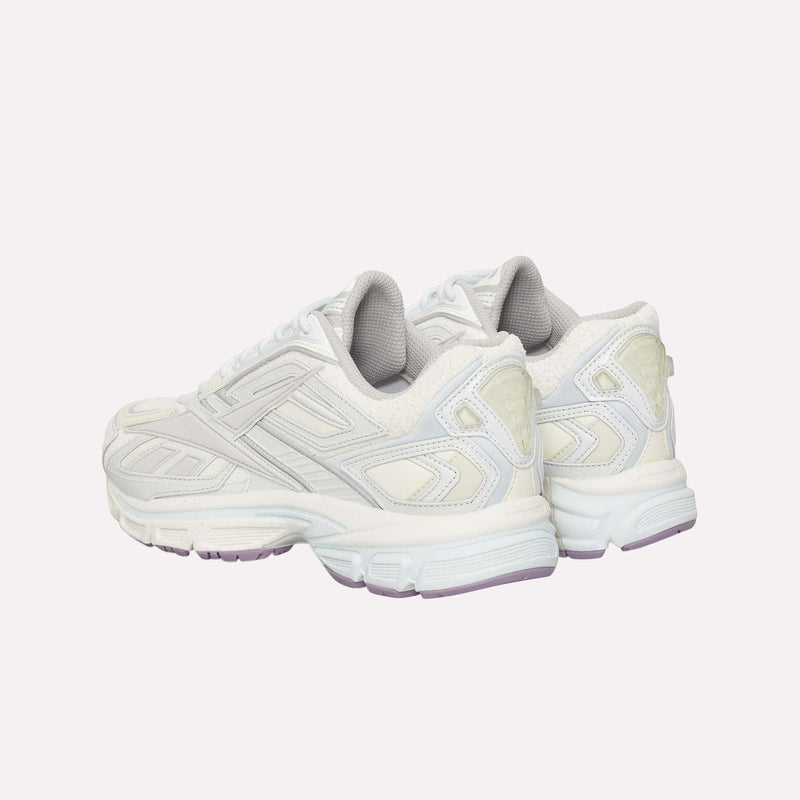 A pair of Premier Road Ultra LTD Shoes by Reebok in white with light gray accents, shown from the back and side on a plain, light background. Drawing inspiration from an archival running silhouette, these sneakers offer enhanced comfort and support with their dual-density midsole.