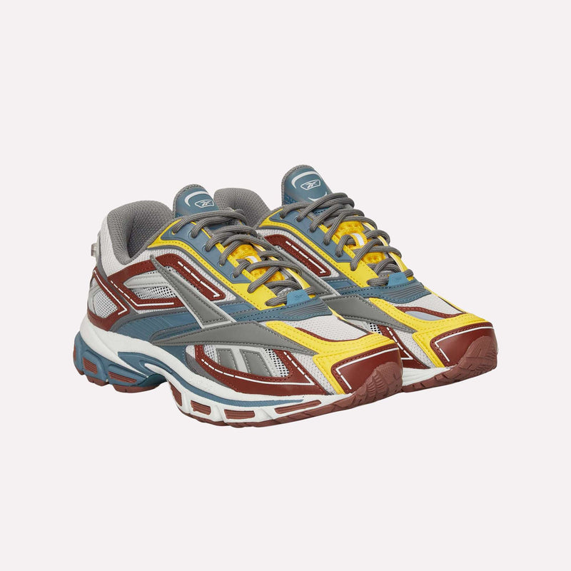 The Reebok Premier Road Ultra LTD Shoes are showcased against a plain white background. These running sneakers display a vibrant multicolor design with gray, yellow, red, blue, and white accents and feature a dual-density midsole for enhanced comfort and support.