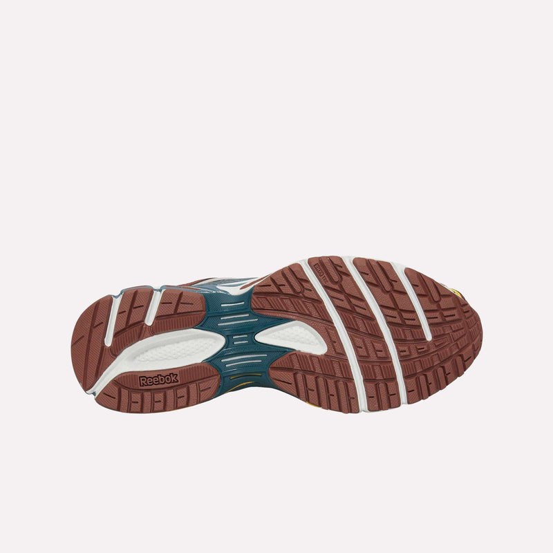 The image shows the bottom view of the Reebok Premier Road Ultra LTD Shoes, featuring a brown, white, and teal rubber outsole with grooves and treads for traction, and a dual-density midsole designed for enhanced comfort and support.