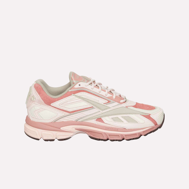 Showcased from the side against a plain, light background, the Reebok Premier Road Ultra LTD Shoes feature a pink and white design with mesh and suede panels, white laces, and a thick, textured dual-density midsole—drawing inspiration from archival running sneaker aesthetics.