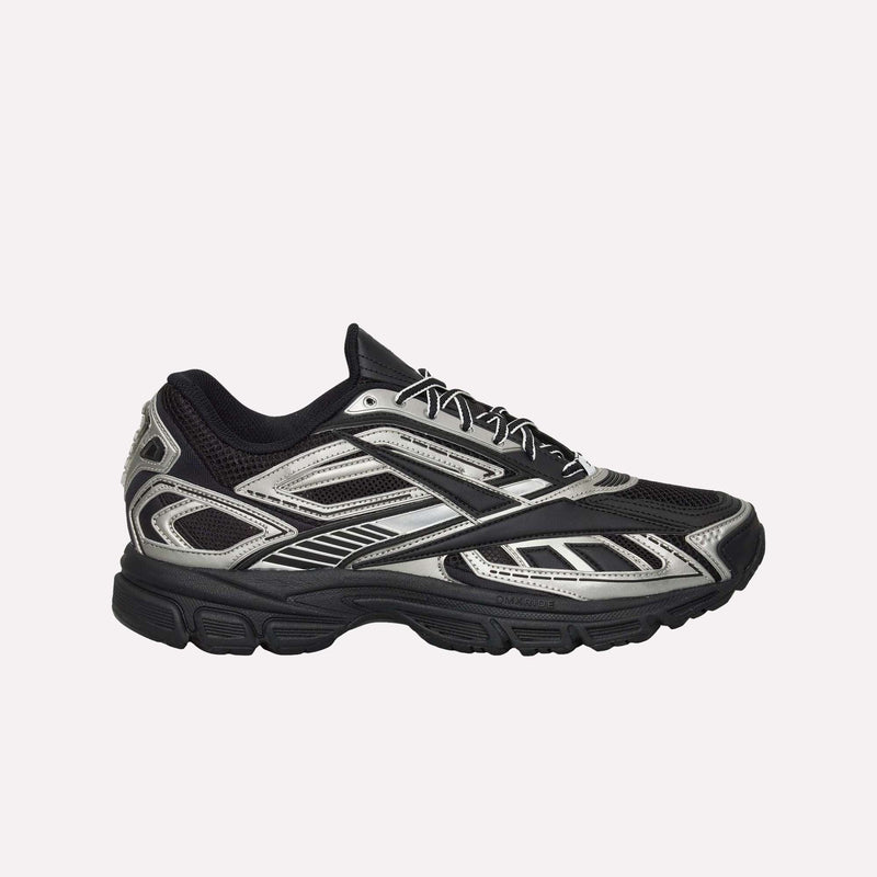 The Reebok Premier Road Ultra Shoes are displayed in side profile against a plain white background, featuring a black and silver design with a mesh upper, geometric patterns, and a thick textured sole with a dual-density midsole.