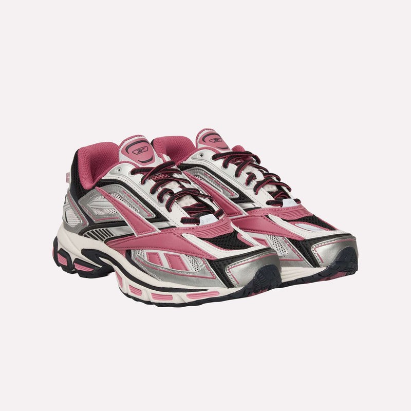 Introducing the Reebok Premier Road Ultra Shoes—a pair of athletic sneakers designed with pink, silver, black, and white accents. Crafted from breathable mesh and durable synthetic materials, these shoes feature thick soles with a dual-density midsole for superior comfort. The lace-up closure ensures a secure fit. Inspired by the archival running silhouette of the Reebok Premier Road Ultra, this style seamlessly combines classic design elements with contemporary performance technology.