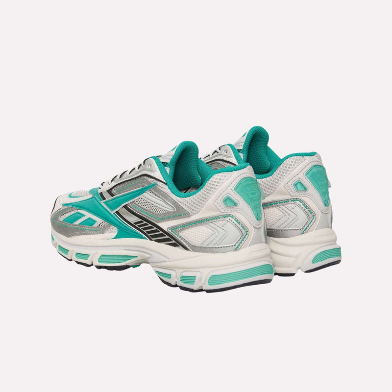 A pair of Reebok Premier Road Ultra Shoes in white and teal, accented with black and silver details, are shown from the back and side angles to highlight their archival running sneaker design and dual-density midsole, all set against a simple light background.