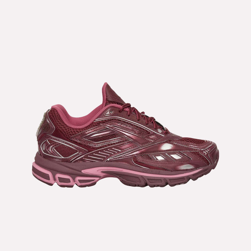 A maroon and pink athletic sneaker from Reebok, the Premier Road Ultra Shoes combine mesh with synthetic accents and draw inspiration from an archival running silhouette. The design includes a dual-density midsole for enhanced comfort and is displayed in a side profile against a plain white background.