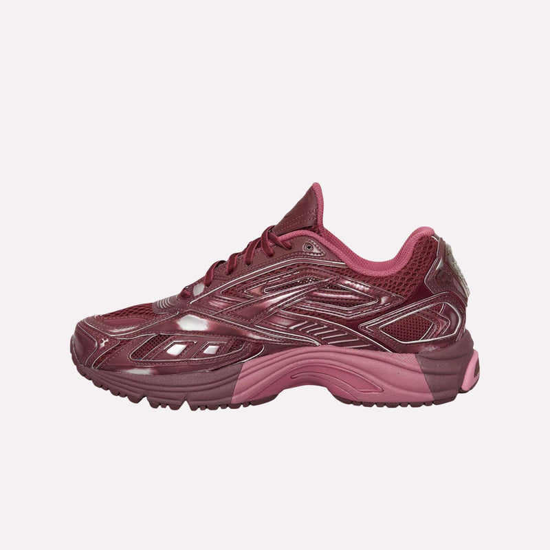 The Reebok Premier Road Ultra Shoes are displayed in a side view against a plain white background, showcasing maroon and pink tones with both shiny and matte finishes. Featuring a chunky, dual-density midsole and detailed paneling, the design draws inspiration from an archival running sneaker.