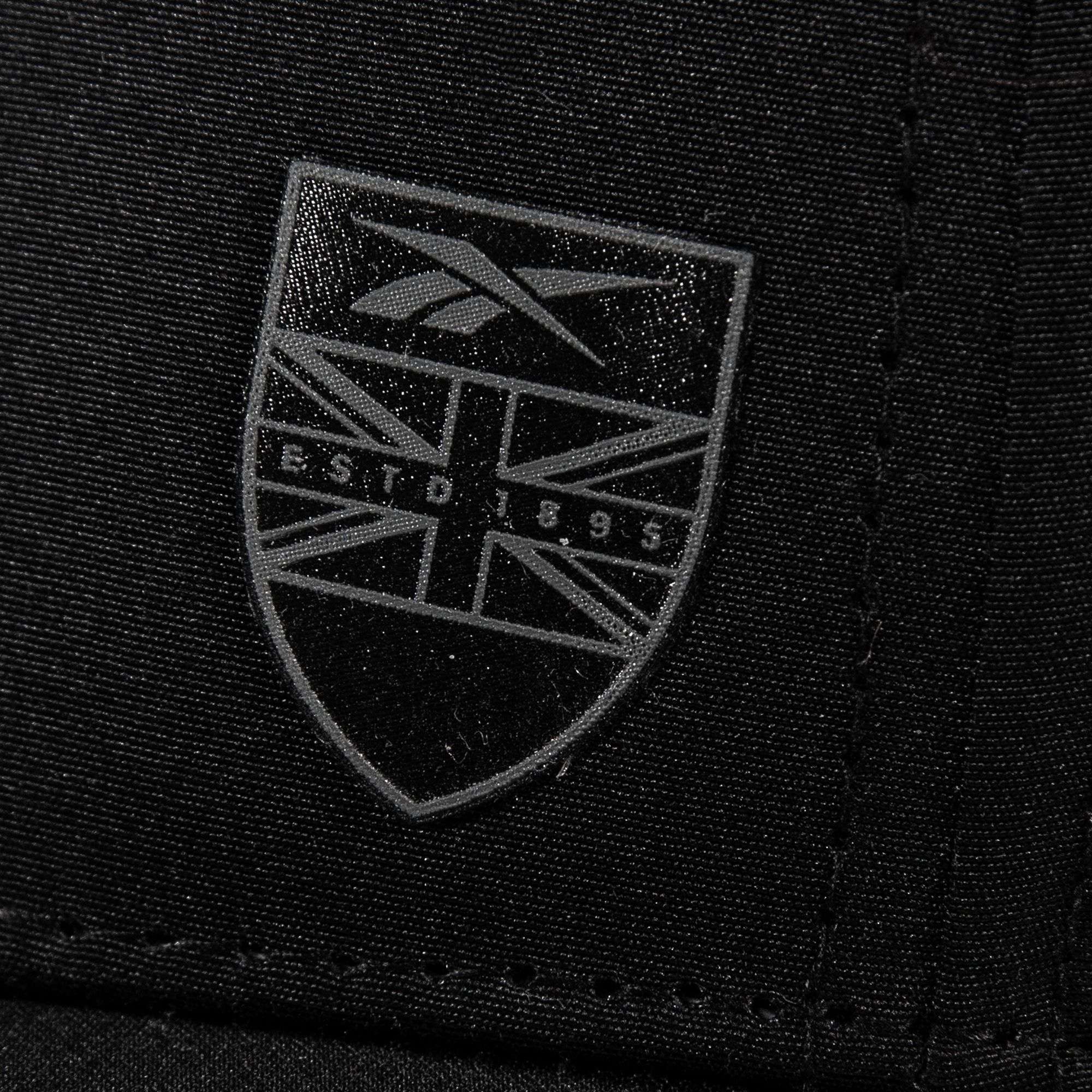 Close-up of black Chip Pro fabric by Reebok, showcasing a shield-shaped logo with the Union Jack pattern and gray "ESTD 1895" text.