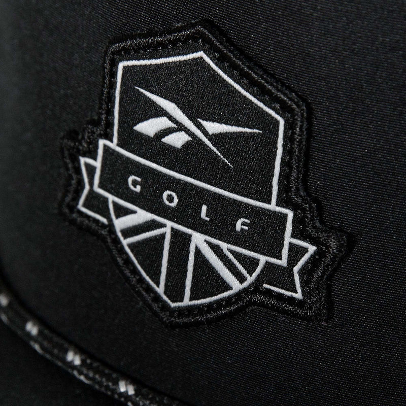 A close-up of the Madison Ii by Reebok shows a black patch with a white shield and stylized logo reading "GOLF" in bold, featured on a recycled polyester hat with an adjustable snapback.