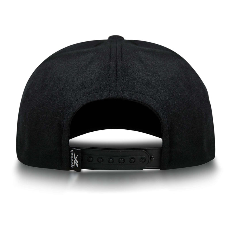 The Reebok Madison Ii is a black recycled polyester hat with an adjustable snapback closure and a small folded tag featuring the Reebok logo on the left side, viewed from the back.