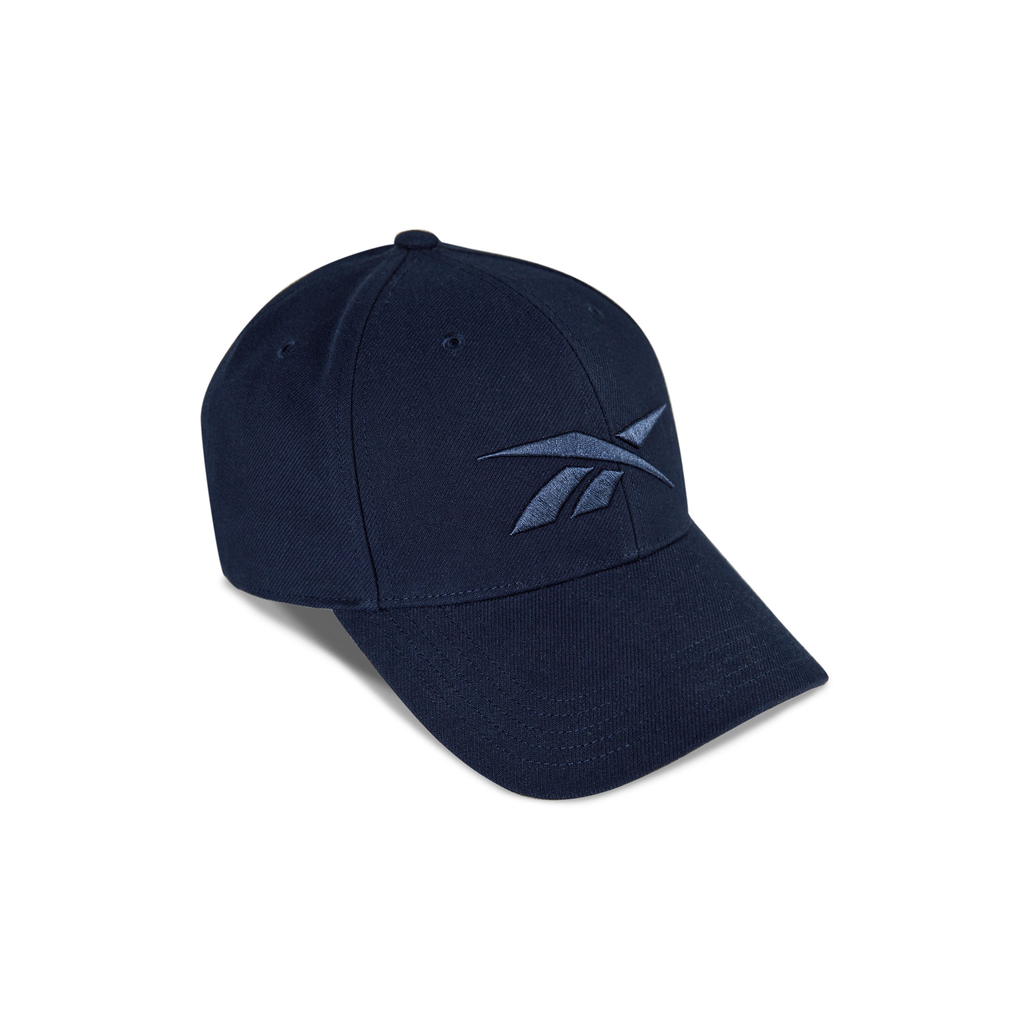 The Vector Baseball Cap by Reebok is navy blue with a curved brim, adjustable snapback, and embroidered front logo, shown on a white background.