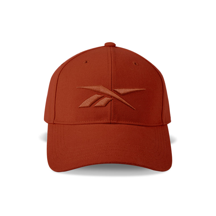 The Vector Baseball Cap by Reebok features a rust-red design, curved brim, adjustable snapback closure, and a matching rust-red embroidered Reebok logo on the front.