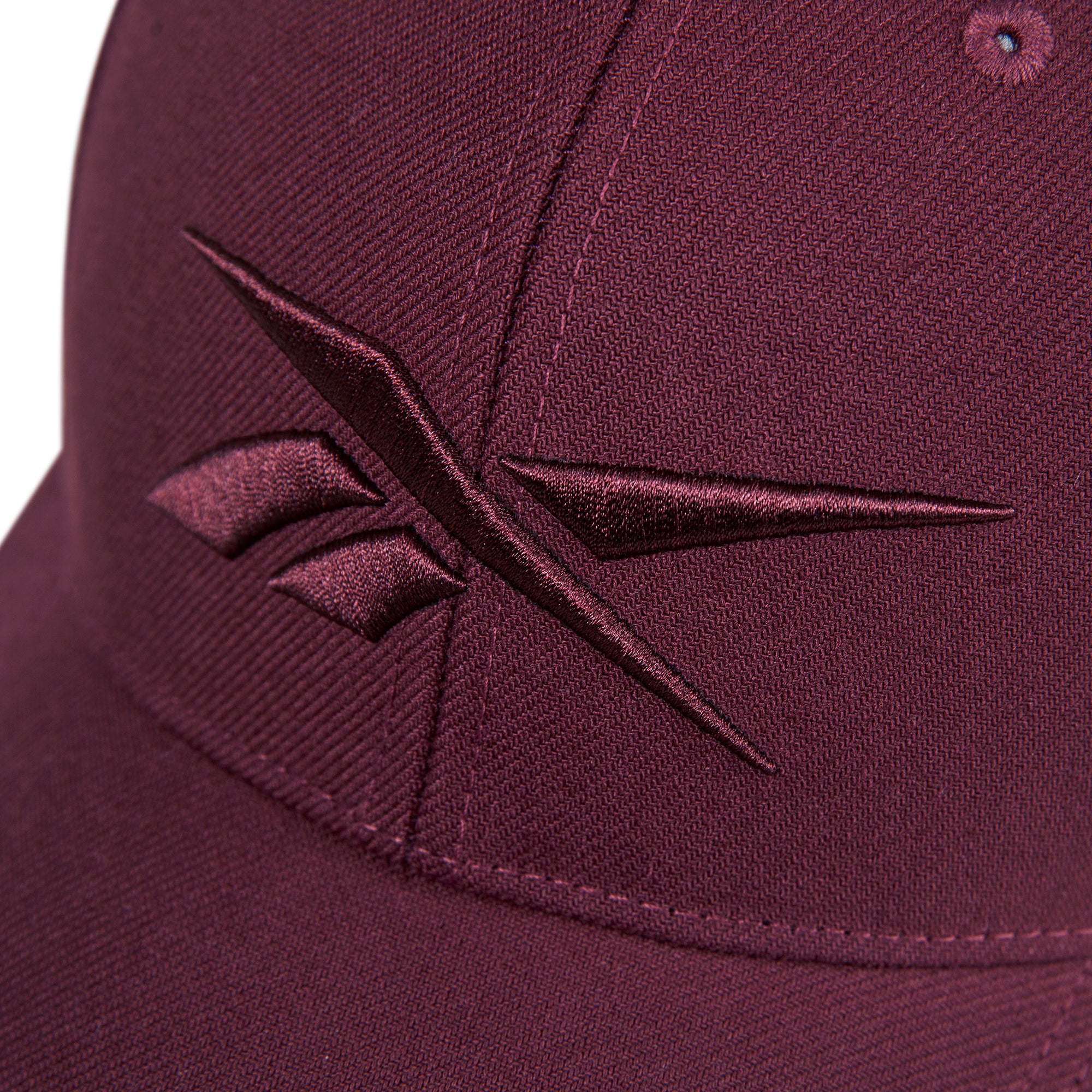 Close-up of the Reebok Vector Baseball Cap in maroon, featuring a maroon embroidered Reebok logo on the front.