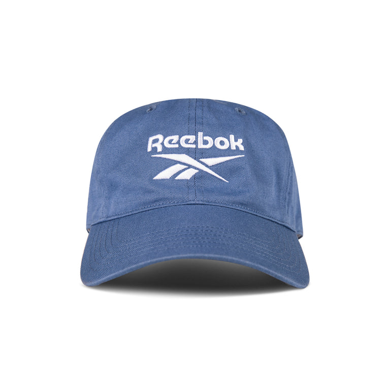 The Reebok Logo Cap features a curved brim and front white logo embroidery. Made from cotton twill with an adjustable buckle for comfort, this cap is shown against a white background.