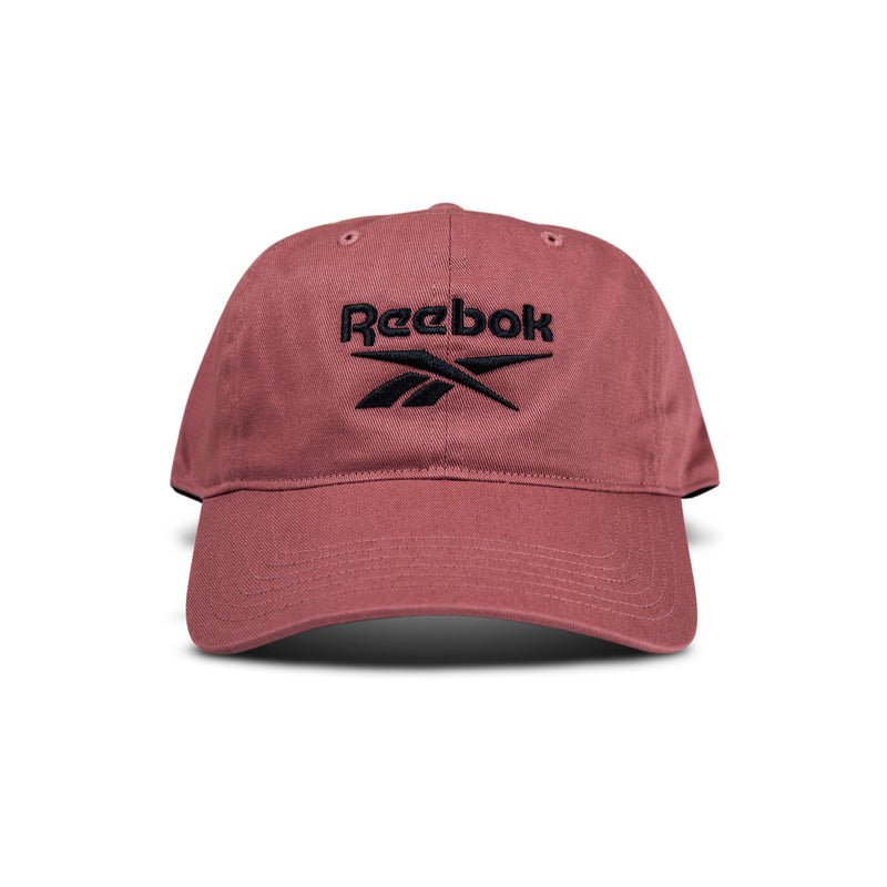 The Reebok Logo Cap is a maroon cotton twill cap with a curved brim and black embroidered logo on the front. It features an adjustable buckle closure and is shown against a white background.