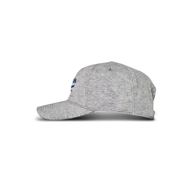 The Reebok Jersey Logo Cap is shown from the side in grey heather, featuring a curved brim, visible stitching, and a partially visible blue and red logo on the front against a plain white background.