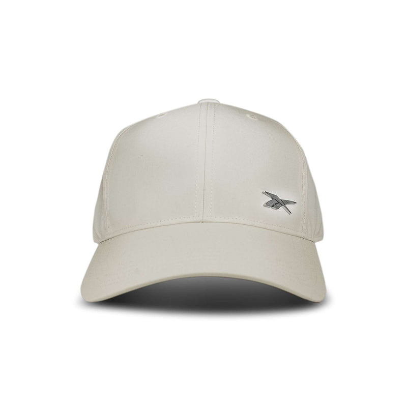 The Reebok Badge Cap is a beige baseball cap featuring a small silver embroidered logo on the front left side, shown against a white background.