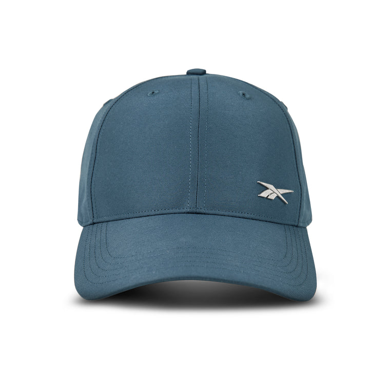 The Reebok Badge Cap is a blue adjustable sports hat with a curved brim, small silver logo on the front left, visible stitching, top button, and moisture-wicking comfort.