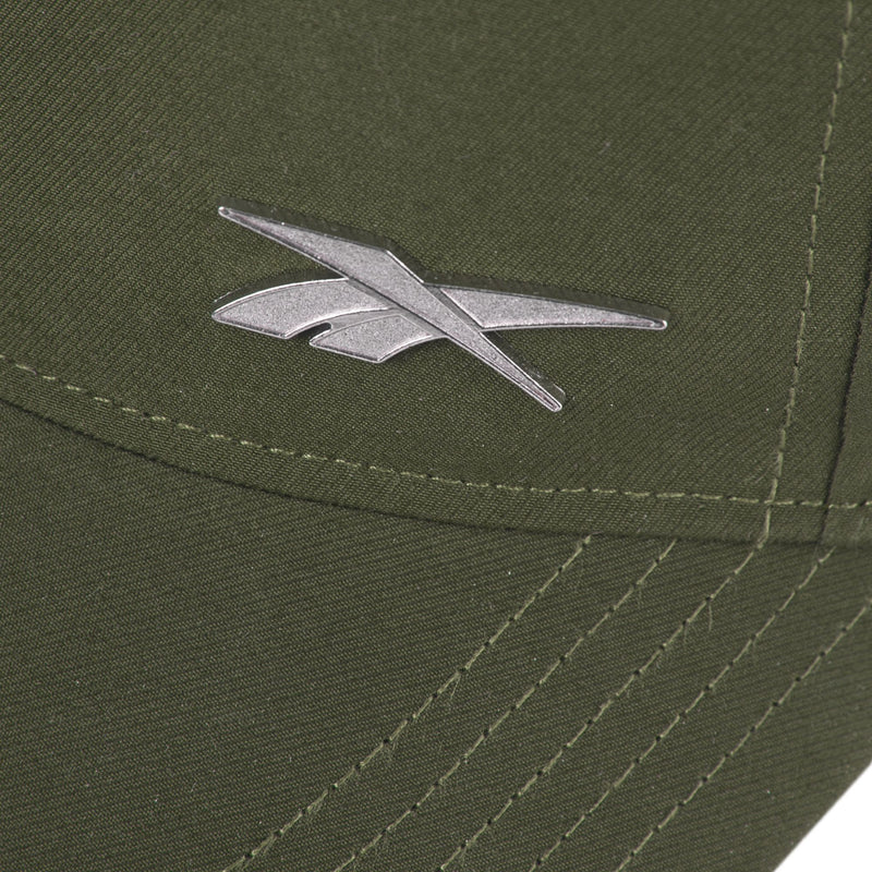 Close-up of the silver Reebok logo on olive green fabric of the Reebok Badge Cap, featuring visible stitching and intersecting seams.