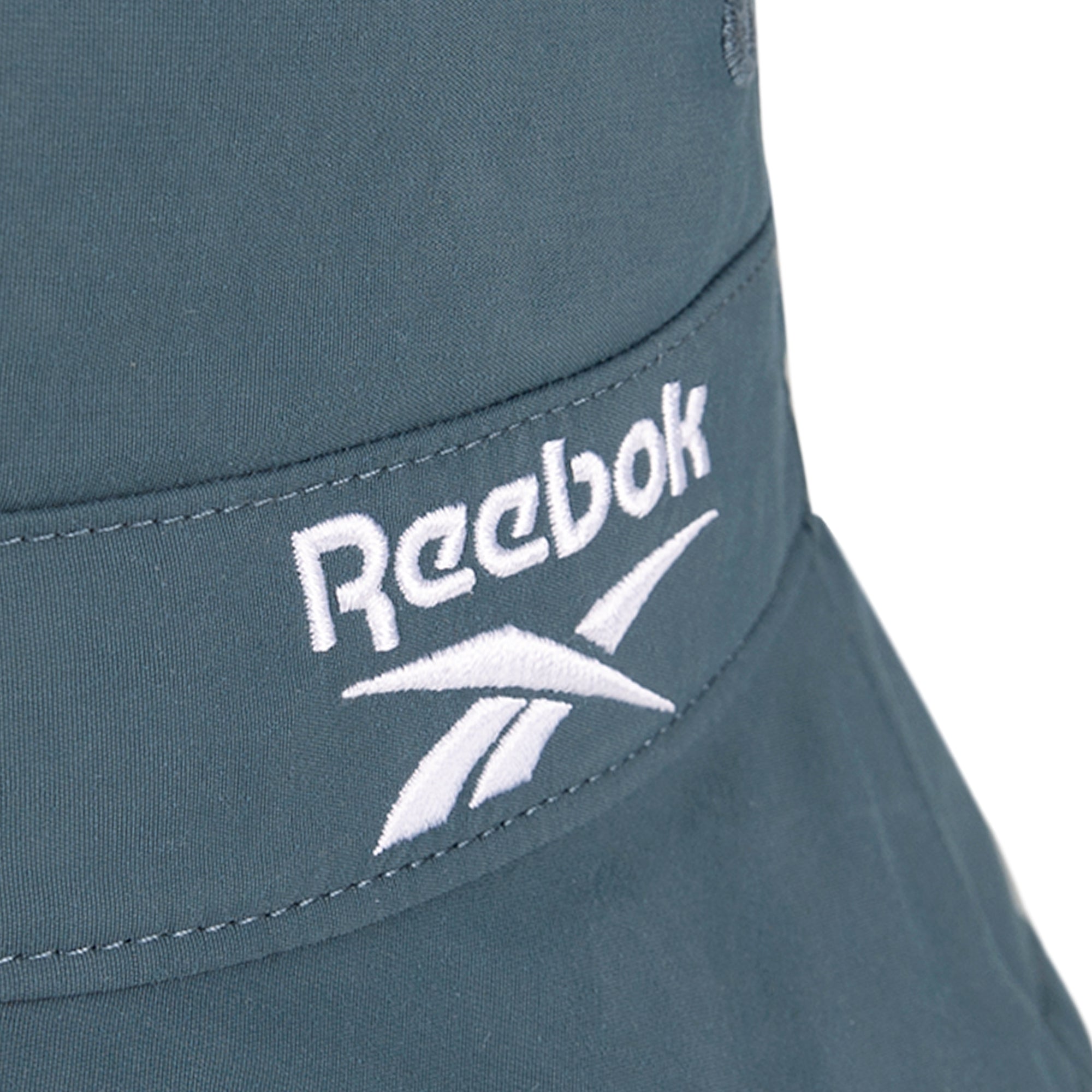 Close-up of a blue Reebok Bucket Hat with the brand's logo and name embroidered in white on recycled nylon fabric.