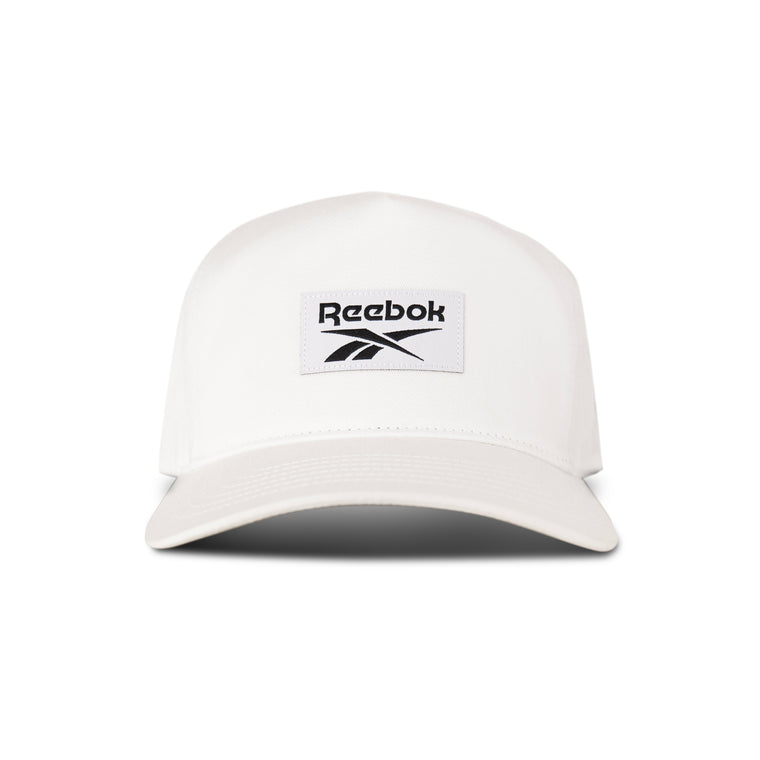The Reebok Classic 5 Cap is displayed from the front, featuring a white 5-panel design with a black Reebok logo on a rectangular patch centered above the brim.