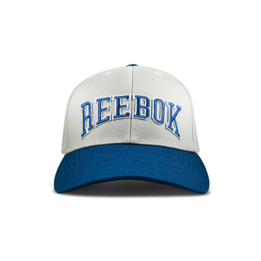 The Reebok Gameday Cap, shown front-facing on a white background, features vintage styling in white and blue with bold blue "REEBOK" embroidery on the front.