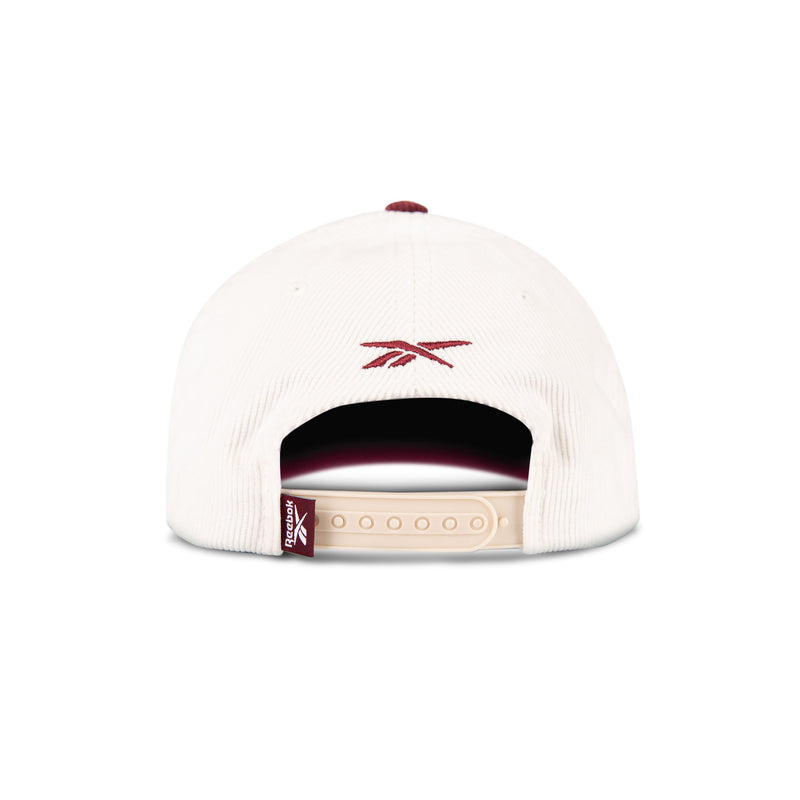 A white corduroy baseball cap from Reebok’s Corduroy Gameday Cap collection, seen from the back with a maroon logo, beige snapback strap, and a small maroon Reebok tag on the left side.