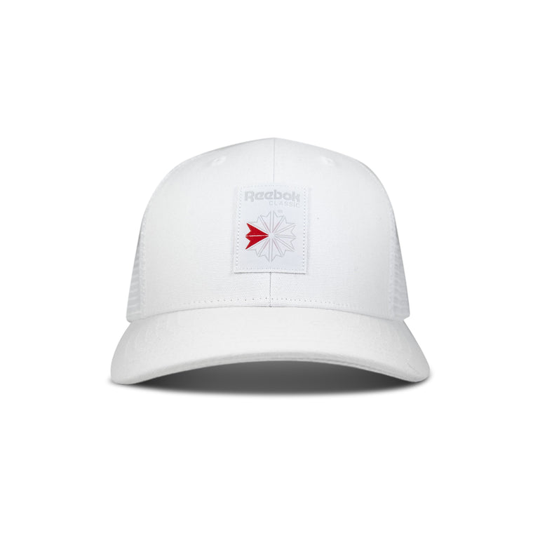 The Reebok Woven Patch Vector Trucker Cap is a white cap with mesh back panels and a rectangular patch on the front featuring the Reebok logo in gray with a red accent.