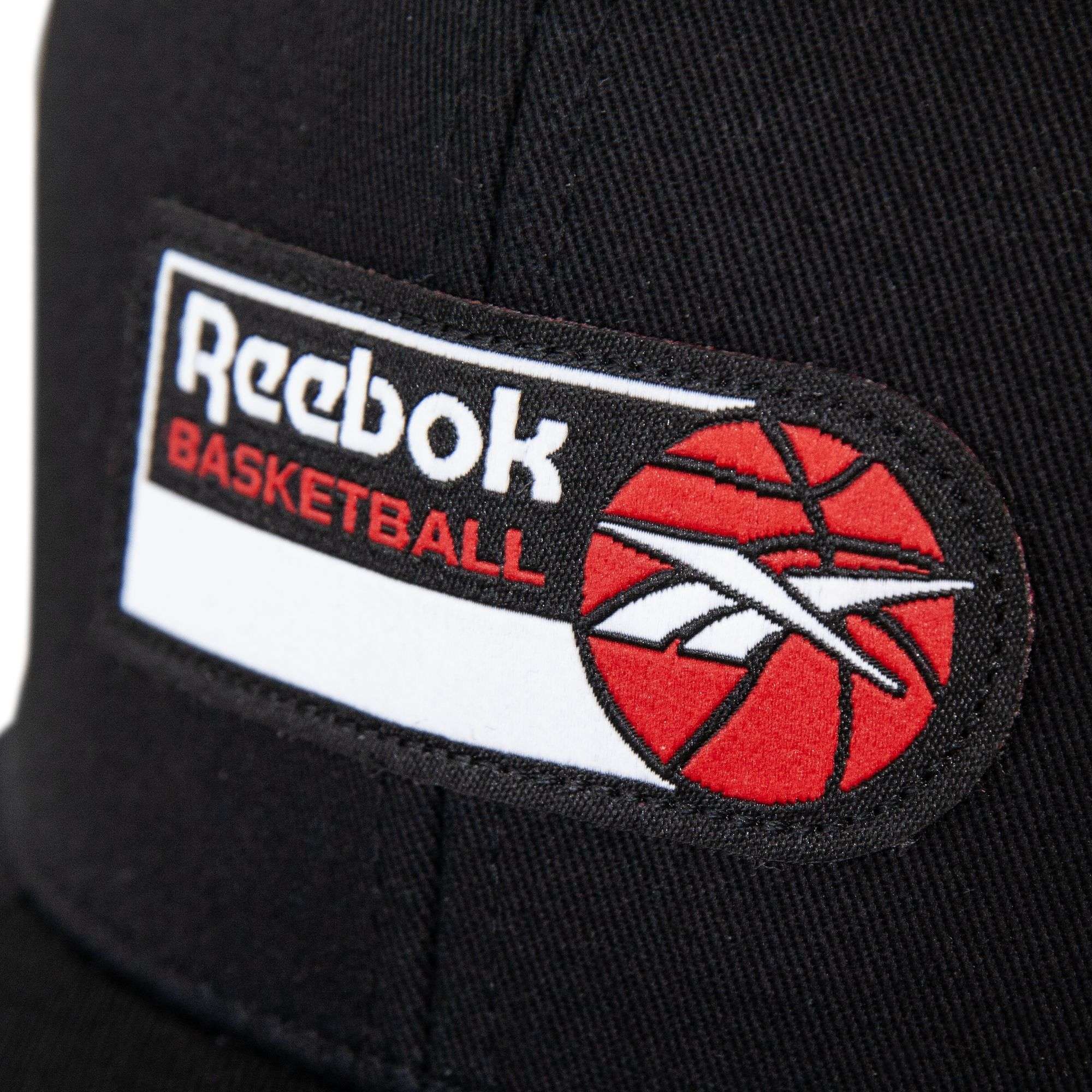 Close-up of a black fabric patch with the Reebok logo, red "BASKETBALL" text, and a red basketball graphic on this stylish Reebok Basketball Trucker Cap—an ideal addition to any basketball hat collection.