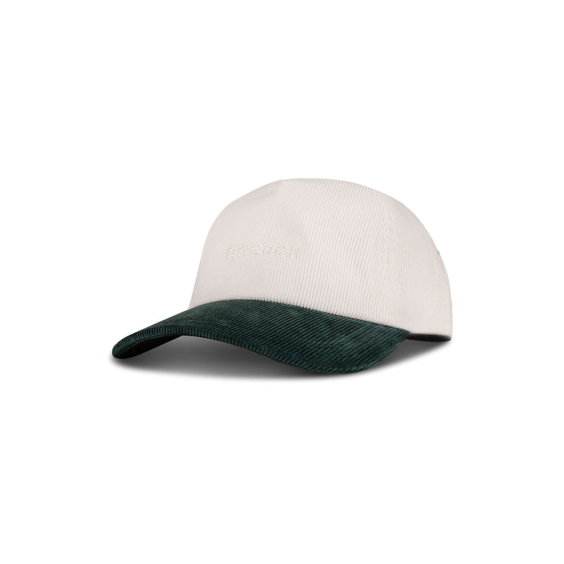 The Reebok Logo Corduroy Cap features a beige corduroy crown, dark green curved brim, adjustable snapback for comfort, and subtle Reebok logo embroidery on the front, shown against a white background.