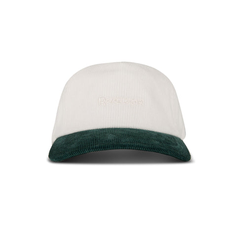 The Reebok Logo Corduroy Cap features a white corduroy crown, dark green brim, "Recess" embroidered in white on the front, and an adjustable snapback for comfort.