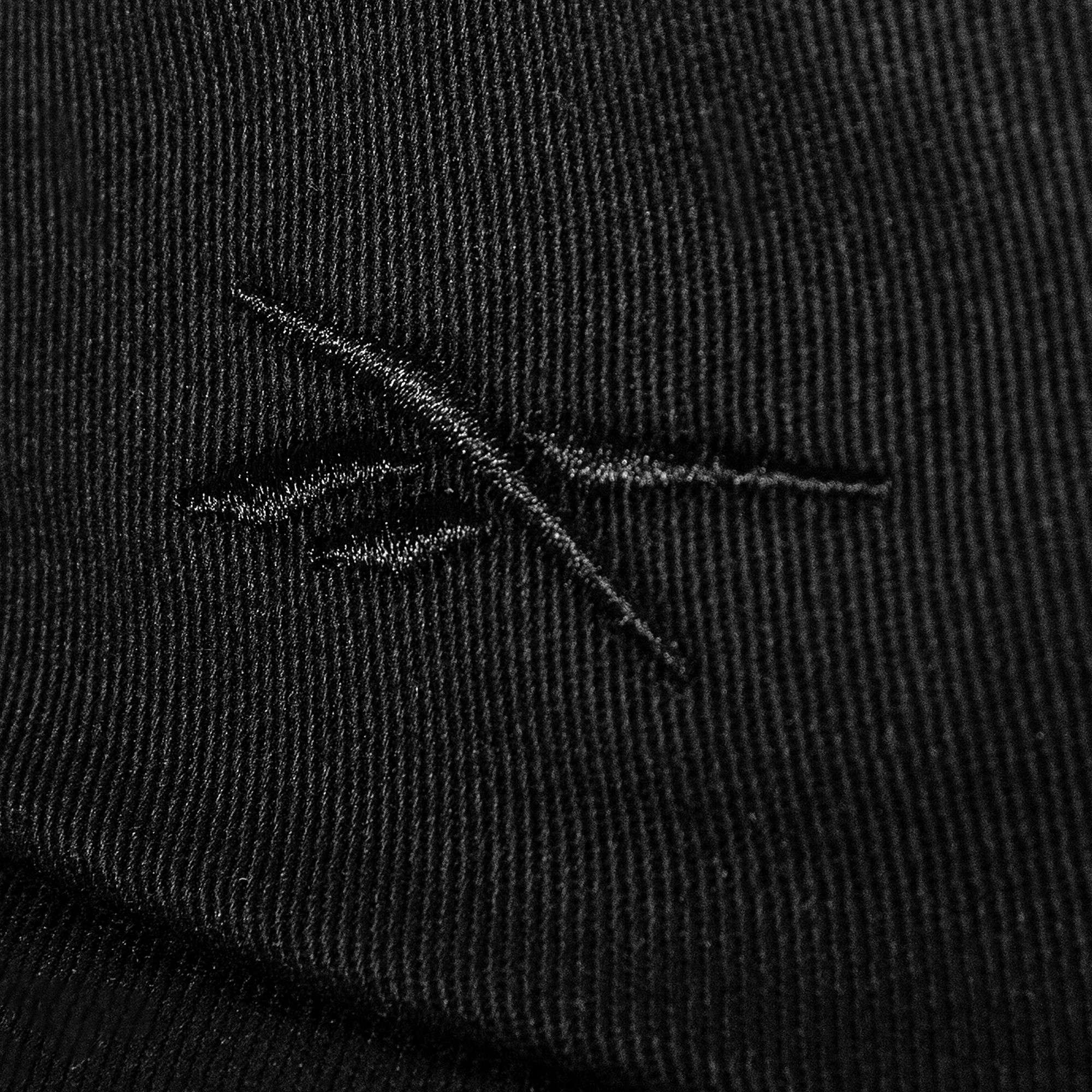Close-up of black cotton twill fabric on the Reebok Logo S-Vector Cap, featuring a stitched abstract crossed-lines logo and textured pattern on an adjustable snapback.