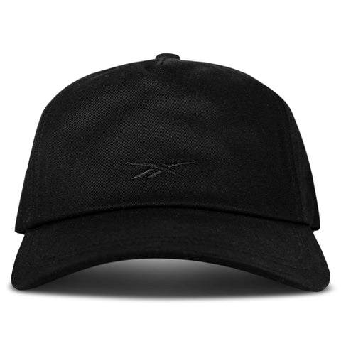 The Reebok Logo S-Vector Cap is a black cotton twill hat with a curved brim and subtle black embroidered front logo. It features an adjustable snapback for comfort, shown here against a plain white background.