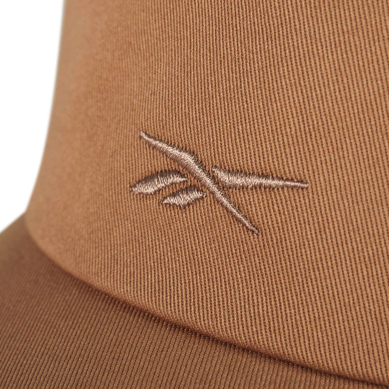Close-up of the Reebok Logo S-Reebok Vector Cap in brown, featuring a subtle embroidered logo with two intersecting lines and leaf-like shapes stitched in lighter brown thread.
