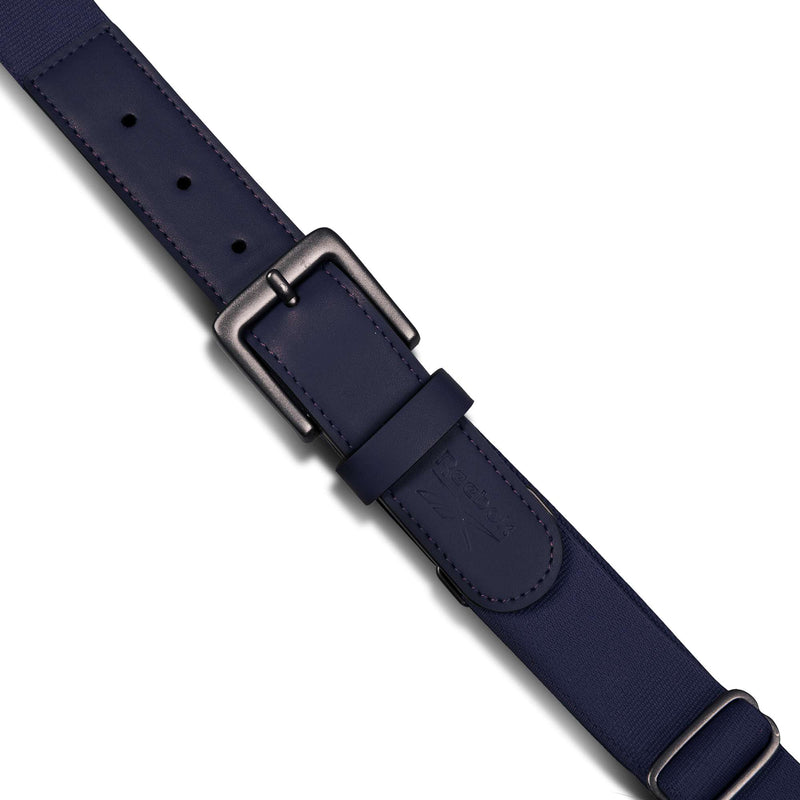 A close-up of the Reebok Youth Baseball Belt in navy blue, featuring stretch elastic material, multiple adjustment holes, an embossed logo, stitched edges, and a matte black adjustable metal buckle with a textured finish.