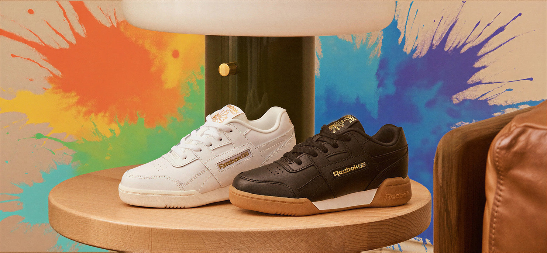 Two pairs of sneakers on a wooden stand with a colorful abstract background