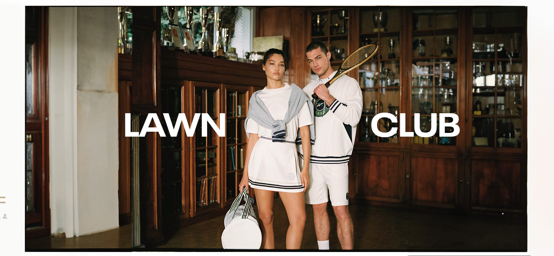 Two people standing in a bar with 'Lawn Club' branding.