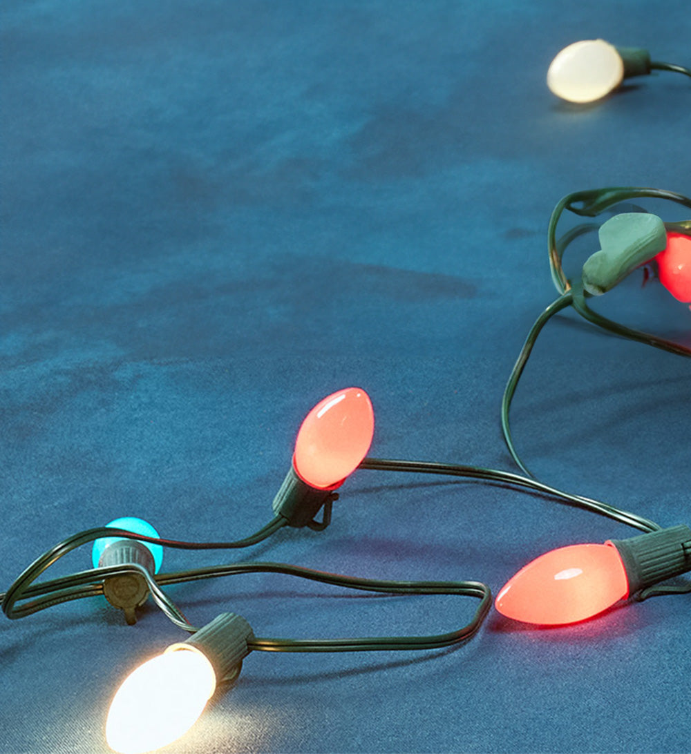String of multicolored Christmas lights on a blue surface