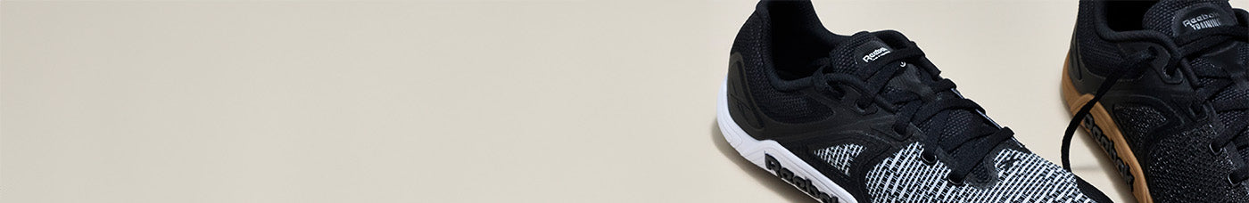 Black athletic shoes with white soles on a beige background