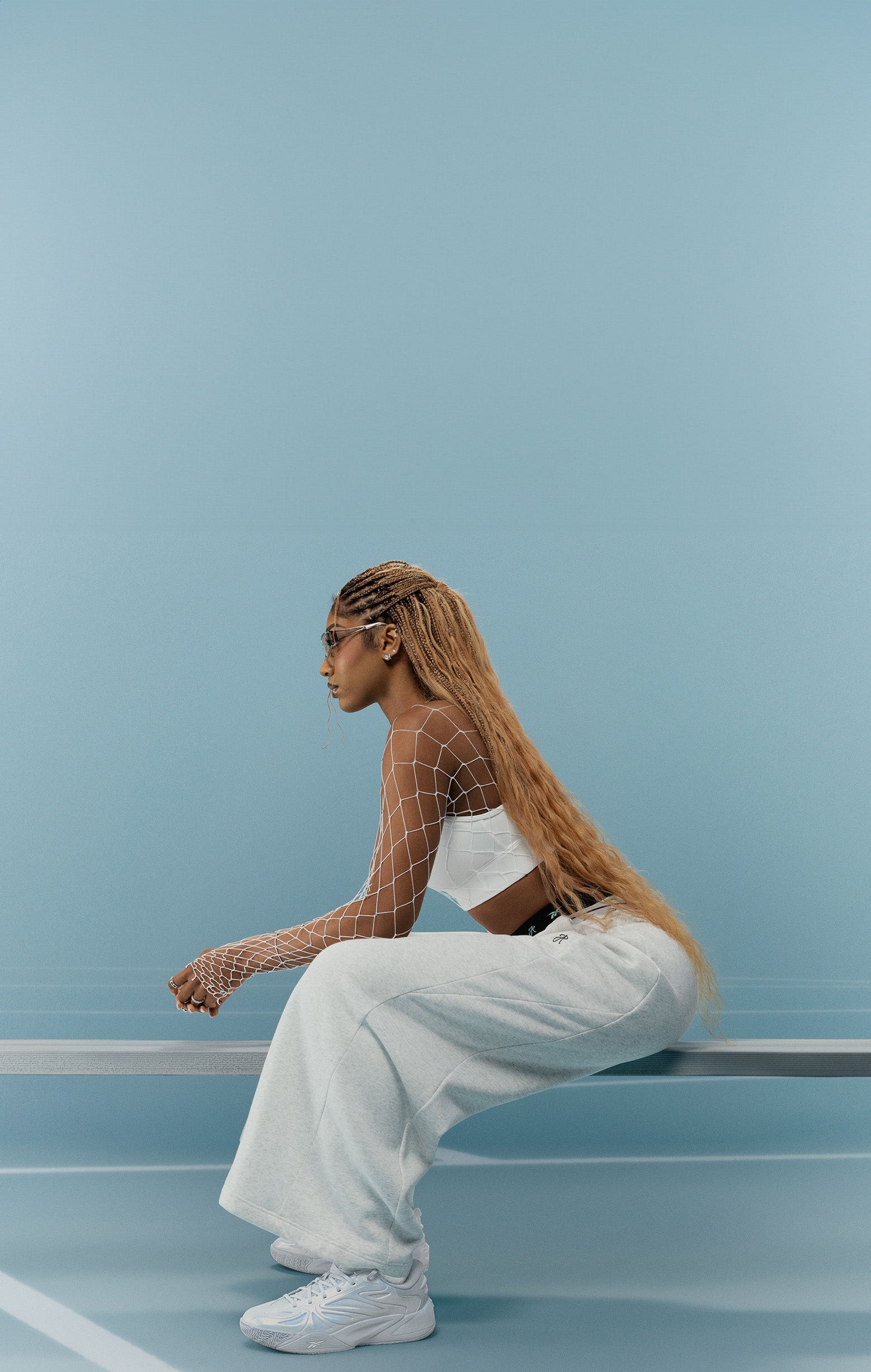 Woman sitting on a blue wall with a minimalistic background